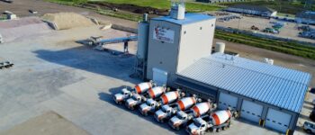 Aerial view of Buffalo Ridge Concrete Inc. with mixer trucks parked outside and material piles nearby.