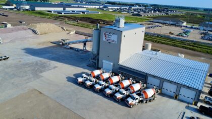 Aerial view of Buffalo Ridge Concrete Inc. with mixer trucks parked outside and material piles nearby.
